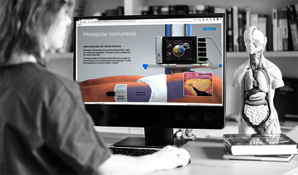 Eine Frau schaut in einen Bildschirm mit der e-learning Plattform für Elektrochirurgie. 